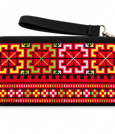 Black handmade Palestinian embroidered clutch with colorful geometric cross-stitch patterns in red, yellow, green and pink, and a detachable wrist strap.