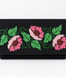 Small black handmade Palestinian embroidered clutch with three pink cross-stitch flowers, green leaves and no wrist strap.